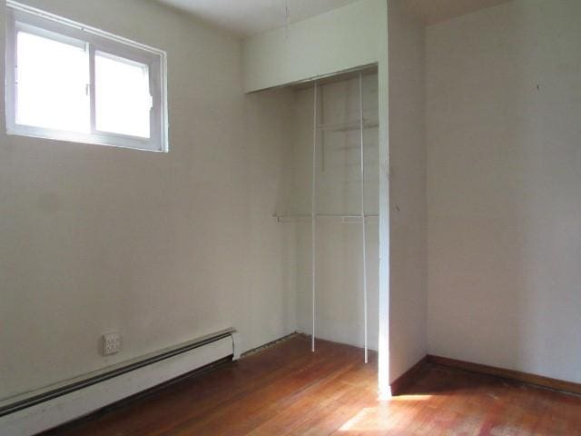 129 Windsor Dr, Penn Hills, PA 15235 - unfurnished bedroom with a baseboard radiator, a closet, and light wood-style flooring