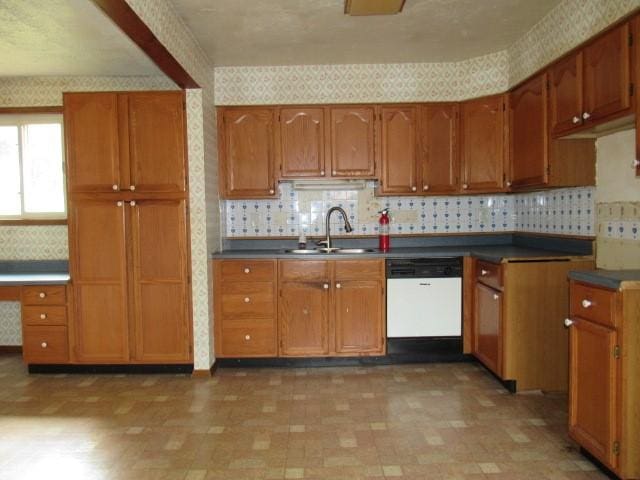 129 Windsor Dr, Penn Hills, PA 15235 - kitchen featuring white dishwasher, wallpapered walls, brown cabinets, decorative backsplash, and light floors
