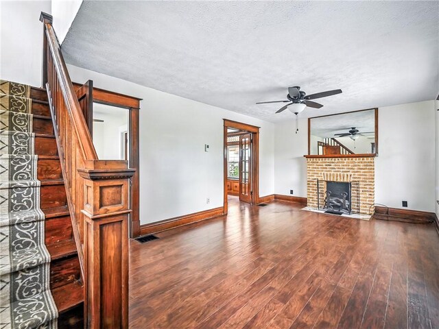 385 Spruce Ave, Sharon, PA 16146 - unfurnished living room featuring ceiling fan, a textured ceiling, a fireplace, wood finished floors, and stairs