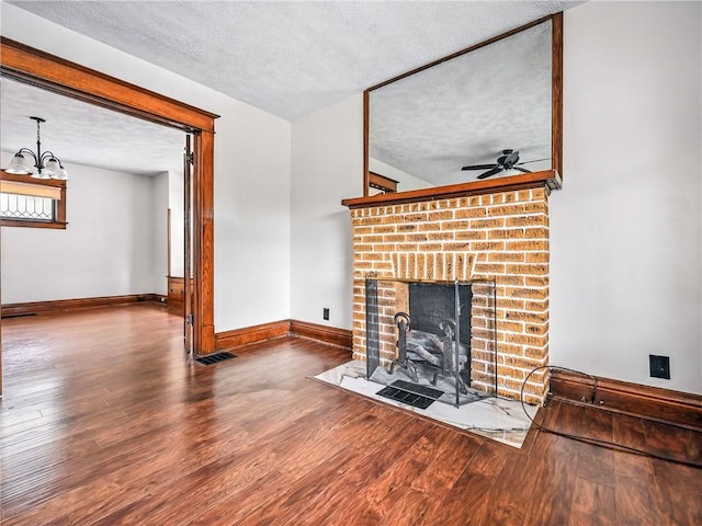 385 Spruce Ave, Sharon, PA 16146 - unfurnished living room with a textured ceiling, wood finished floors, a fireplace, a ceiling fan, and a chandelier