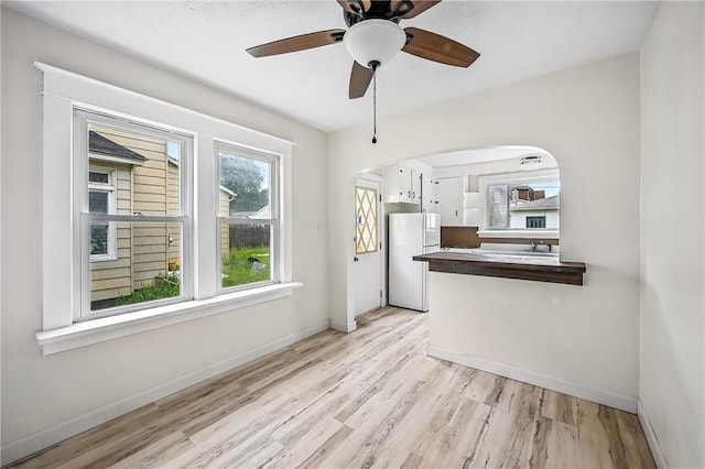 385 Spruce Ave, Sharon, PA 16146 - kitchen with freestanding refrigerator, light wood-type flooring, arched walkways, ceiling fan, and dark countertops