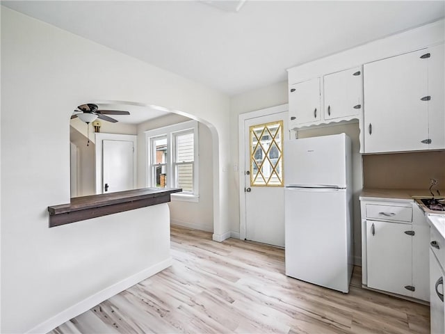 385 Spruce Ave, Sharon, PA 16146 - kitchen with freestanding refrigerator, arched walkways, light wood finished floors, a ceiling fan, and white cabinets