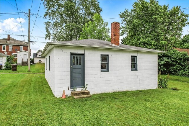 385 Spruce Ave, Sharon, PA 16146 - rear view of house featuring a chimney, a lawn, roof with shingles, and concrete block siding