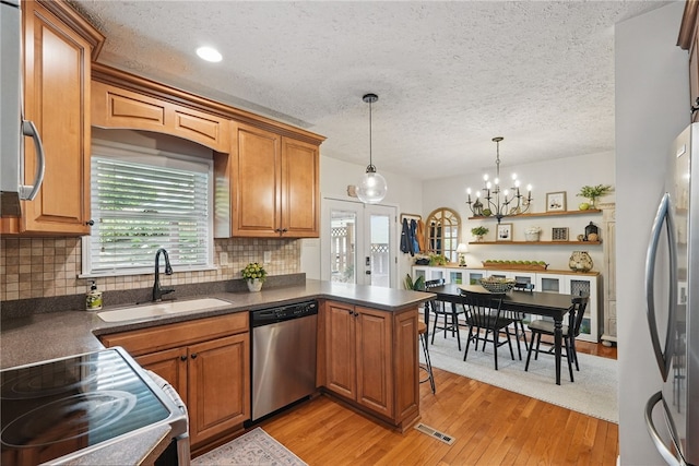3236 Beacon Hill Ave, Dormont, PA 15216 - kitchen with stainless steel appliances, dark countertops, brown cabinetry, a peninsula, and a textured ceiling