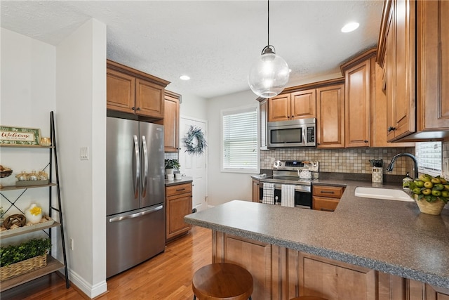3236 Beacon Hill Ave, Dormont, PA 15216 - kitchen with stainless steel appliances, a peninsula, light wood-type flooring, dark countertops, and decorative backsplash