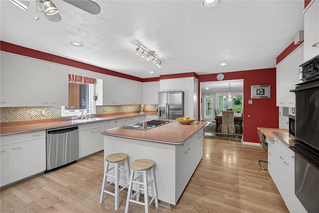 117 Scarborough Ln, Peters Twp, PA 15317 - kitchen with appliances with stainless steel finishes, a center island, light wood finished floors, a textured ceiling, and white cabinets