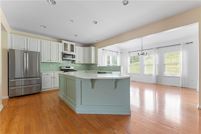4015 Bentwood Dr, North Strabane, PA 15317 - kitchen featuring appliances with stainless steel finishes, light countertops, a chandelier, backsplash, and a kitchen island