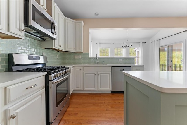 4015 Bentwood Dr, North Strabane, PA 15317 - kitchen with stainless steel appliances, a chandelier, light countertops, light wood-style flooring, and tasteful backsplash