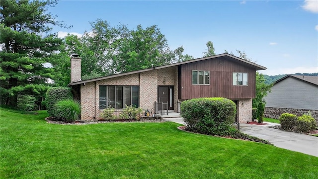 12169 Pine Crest Ct, North Huntingdon, PA 15085 - view of front facade with brick siding, a front yard, concrete driveway, and a chimney