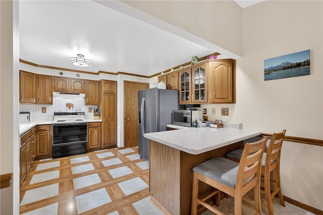 12169 Pine Crest Ct, North Huntingdon, PA 15085 - kitchen with stainless steel appliances, a peninsula, under cabinet range hood, brown cabinetry, and a kitchen bar