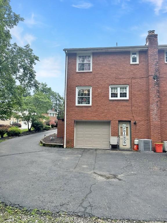 217 S Shady Ave, Chartiers, PA 15342 - view of side of property featuring an attached garage, driveway, brick siding, and a chimney