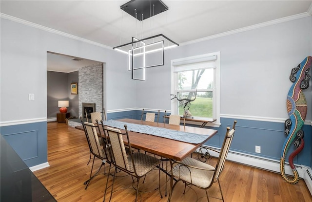 537 Center Church Rd, Peters Twp, PA 15317 - dining area featuring a baseboard radiator, crown molding, wood finished floors, a stone fireplace, and a wainscoted wall