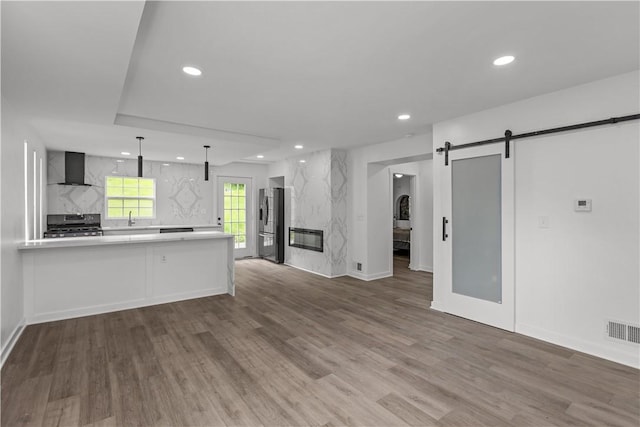 2513 Grove Rd, South Park, PA 15129 - kitchen with a barn door, light countertops, wall chimney exhaust hood, range, and open floor plan