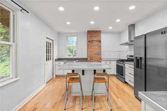 841 Stanton Ave, Millvale, PA 15209 - kitchen with wall chimney exhaust hood, appliances with stainless steel finishes, decorative backsplash, recessed lighting, and light wood-type flooring