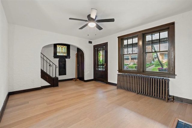 22 Beltzhoover Ave, Allentown, PA 15210 - entrance foyer with radiator heating unit, arched walkways, light wood finished floors, and a ceiling fan