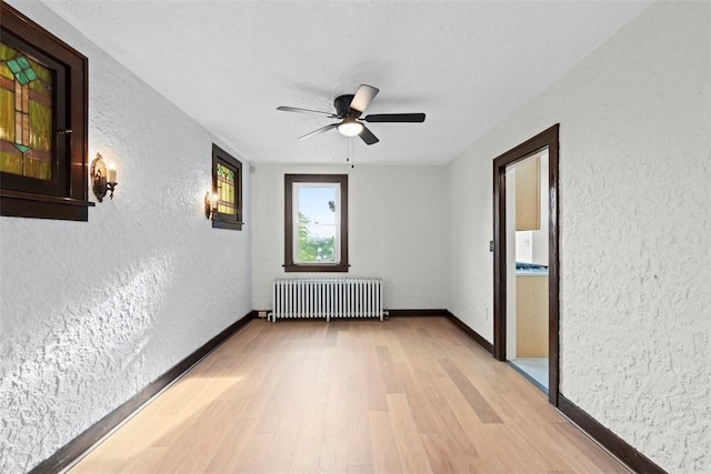 22 Beltzhoover Ave, Allentown, PA 15210 - unfurnished room with radiator heating unit, light wood-style floors, a textured wall, and a ceiling fan