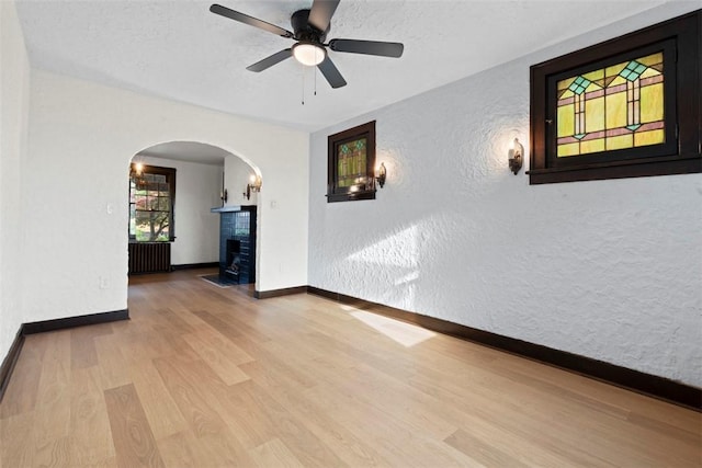 22 Beltzhoover Ave, Allentown, PA 15210 - spare room featuring arched walkways, radiator heating unit, wood finished floors, a textured wall, and a ceiling fan