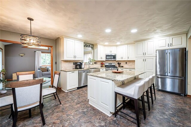 4025 Holiday Park Dr, Murrysville, PA 15668 - kitchen with stainless steel appliances, decorative backsplash, a kitchen island, light stone countertops, and stone finish floors