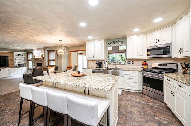 4025 Holiday Park Dr, Murrysville, PA 15668 - kitchen with appliances with stainless steel finishes, open floor plan, a breakfast bar area, recessed lighting, and white cabinetry