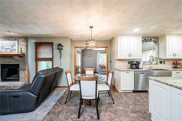 4025 Holiday Park Dr, Murrysville, PA 15668 - kitchen featuring stainless steel dishwasher, open floor plan, white cabinets, backsplash, and hanging light fixtures