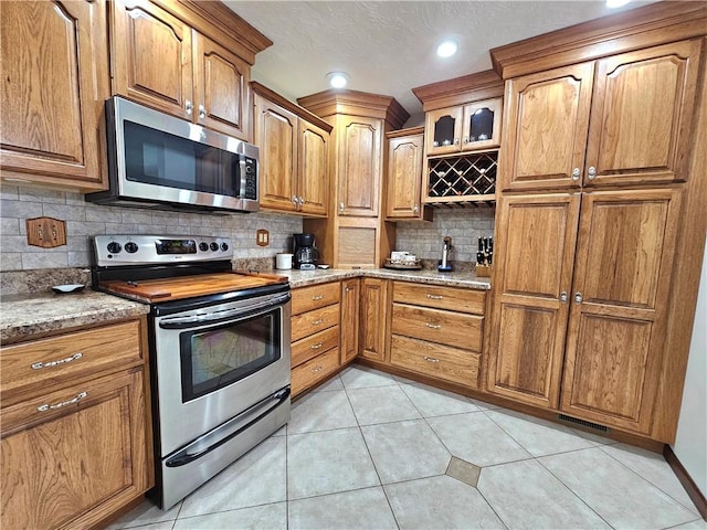 15 Pineview Ests, Sewickley Twp, PA 15089 - kitchen with appliances with stainless steel finishes, backsplash, brown cabinetry, light tile patterned flooring, and recessed lighting