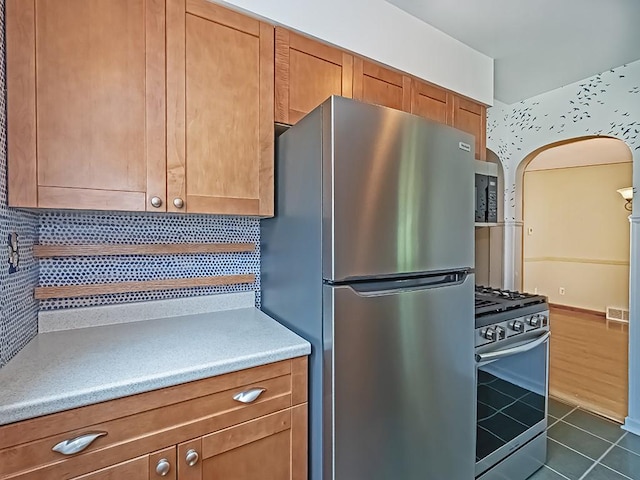 449 Woodland Rd, Canonsburg, PA 15317 - kitchen featuring stainless steel appliances, backsplash, dark tile patterned flooring, arched walkways, and brown cabinets