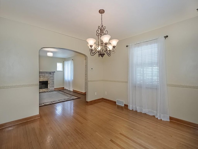 449 Woodland Rd, Canonsburg, PA 15317 - unfurnished dining area with arched walkways, light wood finished floors, a fireplace, and a chandelier