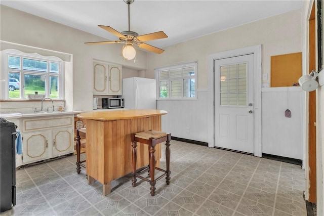 104 Highland Ave, Avella, PA 15312 - kitchen with freestanding refrigerator, stainless steel microwave, a kitchen breakfast bar, a ceiling fan, and range
