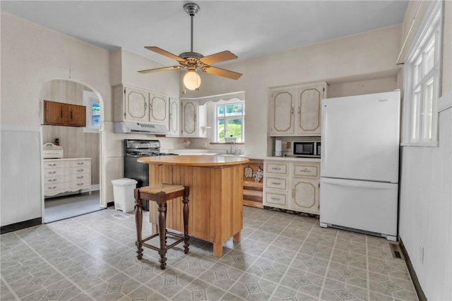 104 Highland Ave, Avella, PA 15312 - kitchen featuring freestanding refrigerator, stainless steel microwave, black range with gas stovetop, a kitchen island, and under cabinet range hood