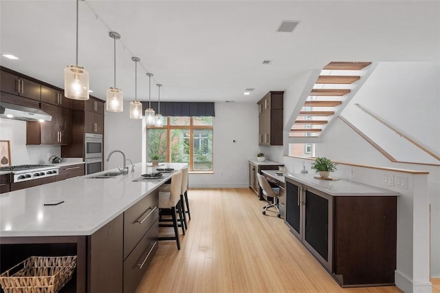 1821 Merriman, South Side, PA 15203 - kitchen featuring stainless steel appliances, light wood finished floors, dark brown cabinetry, a breakfast bar, and a large island with sink
