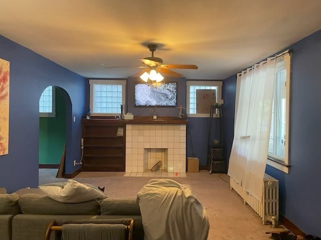 603 Whitney, Wilkinsburg, PA 15221 - living area featuring radiator, arched walkways, carpet, a tiled fireplace, and a ceiling fan