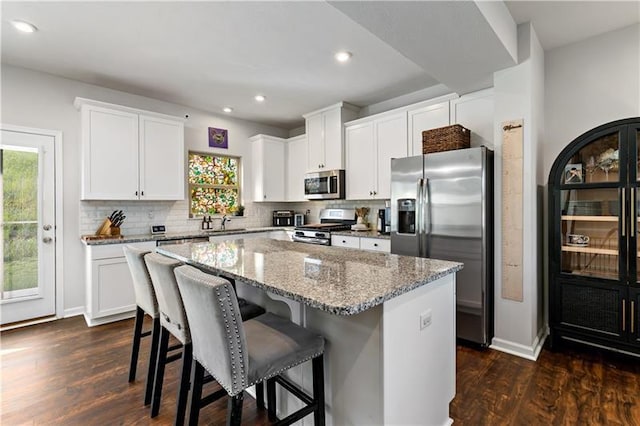 4002 Saint Andrews Ct, Penn Twp Wml, PA 15644 - kitchen featuring appliances with stainless steel finishes, a kitchen island, decorative backsplash, light stone countertops, and recessed lighting