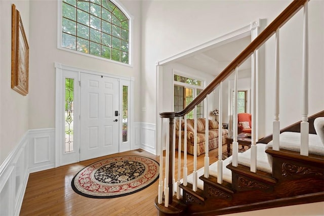 7052 Bennington Woods Dr, Mccandless, PA 15237 - entryway featuring stairway, a decorative wall, wood finished floors, a wainscoted wall, and a towering ceiling