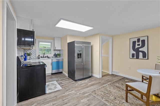 466 Braden School Rd, Chippewa Twp, PA 15010 - kitchen with appliances with stainless steel finishes, light countertops, light wood finished floors, white cabinets, and tasteful backsplash