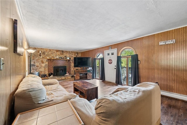 119 Taylor Rd, Quemahoning Twp, PA 15541 - living room featuring wood finished floors, wood walls, a baseboard heating unit, a fireplace, and a textured ceiling