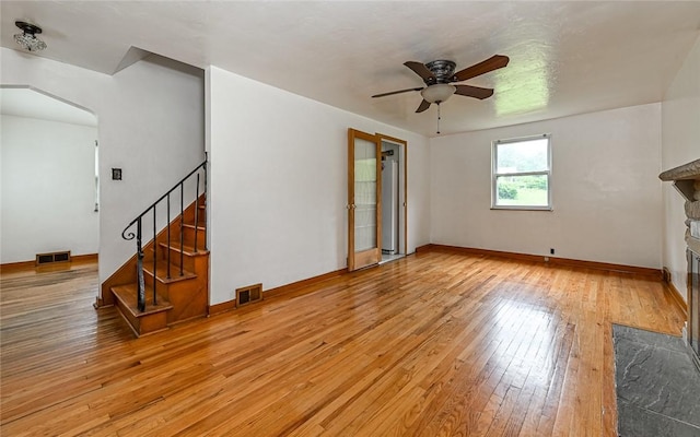 9916 Neuhart Blvd, Mccandless, PA 15090 - unfurnished living room with a ceiling fan, a stone fireplace, light wood-style floors, stairway, and arched walkways