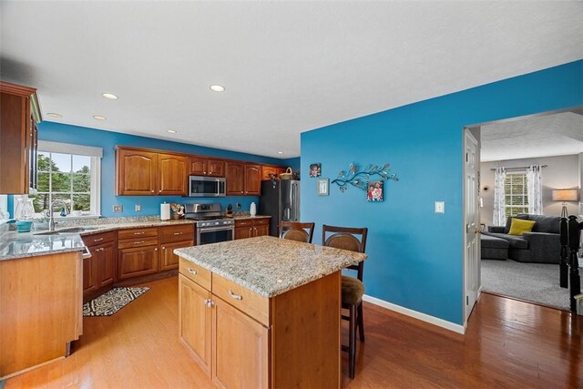 81406 Lost Valley Dr, Adams Twp, PA 16046 - kitchen with stainless steel appliances, light wood finished floors, a center island, a breakfast bar, and light stone counters