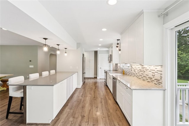 3442 Mercer Rd, Neshannock Twp, PA 16105 - kitchen with light wood-type flooring, white cabinets, decorative backsplash, a breakfast bar, and a peninsula
