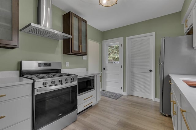 452 Canal St, Beaver, PA 15009 - kitchen with stainless steel appliances, wall chimney exhaust hood, light countertops, light wood-style flooring, and dark brown cabinets