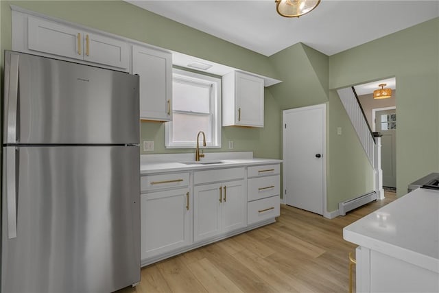 452 Canal St, Beaver, PA 15009 - kitchen featuring freestanding refrigerator, light countertops, a baseboard radiator, white cabinets, and light wood finished floors