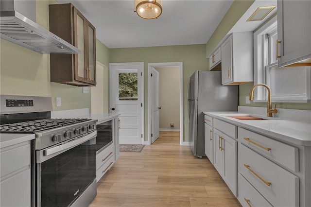 452 Canal St, Beaver, PA 15009 - kitchen with wall chimney range hood, appliances with stainless steel finishes, light countertops, and light wood-style flooring
