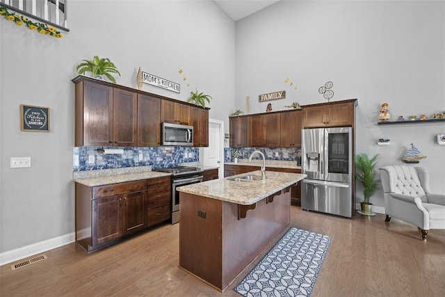 503 Tuscarora Rd, Marshall, PA 16046 - kitchen featuring stainless steel appliances, high vaulted ceiling, decorative backsplash, wood finished floors, and a breakfast bar area