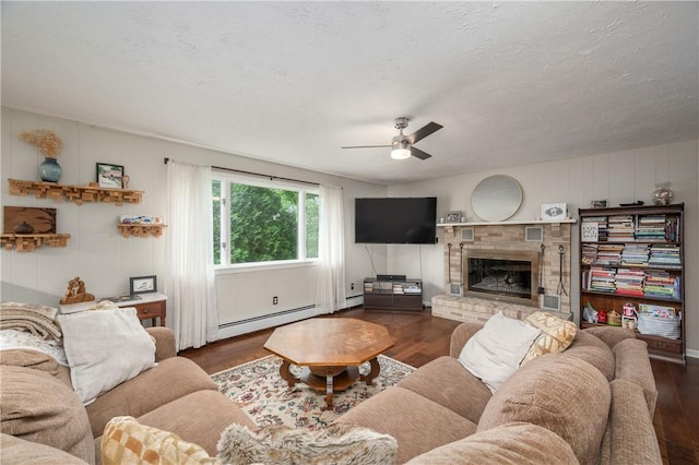 202 Village Ln, New Wilmington Boro, PA 16142 - living room featuring wood finished floors, ceiling fan, a baseboard radiator, a brick fireplace, and a textured ceiling