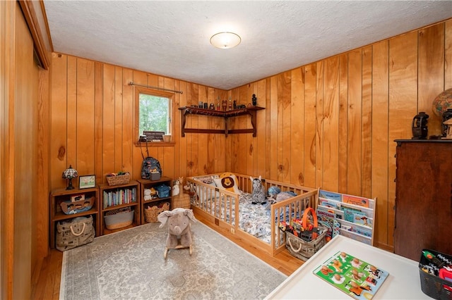 202 Village Ln, New Wilmington Boro, PA 16142 - bedroom featuring wood finished floors, a textured ceiling, and wooden walls