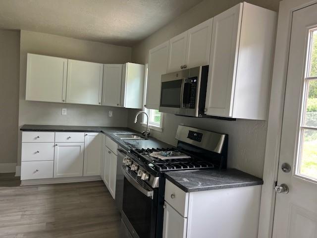 819 Forest St, Latrobe, PA 15650 - kitchen featuring stainless steel appliances, healthy amount of natural light, white cabinetry, and light wood finished floors