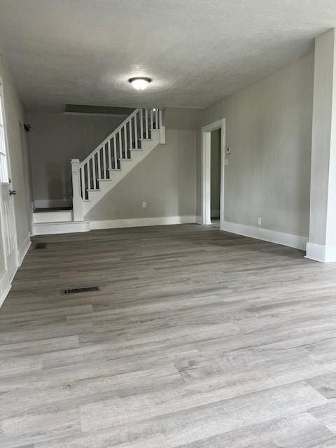 819 Forest St, Latrobe, PA 15650 - unfurnished living room featuring wood finished floors, stairs, and a textured ceiling