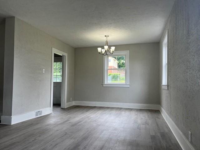 819 Forest St, Latrobe, PA 15650 - spare room with dark wood-style floors, plenty of natural light, a chandelier, a textured wall, and a textured ceiling