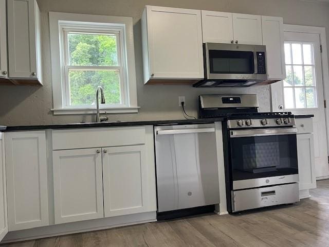 819 Forest St, Latrobe, PA 15650 - kitchen with appliances with stainless steel finishes, dark countertops, white cabinets, and light wood finished floors
