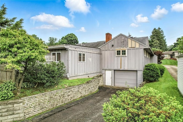 570 S 7th St, Sharpsville, PA 16150 - back of house featuring asphalt driveway, an attached garage, board and batten siding, and a chimney