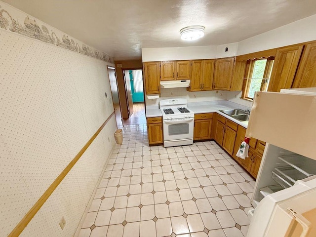 717 King St, Mckeesport, PA 15132 - kitchen with white gas stove, light floors, under cabinet range hood, light countertops, and wallpapered walls